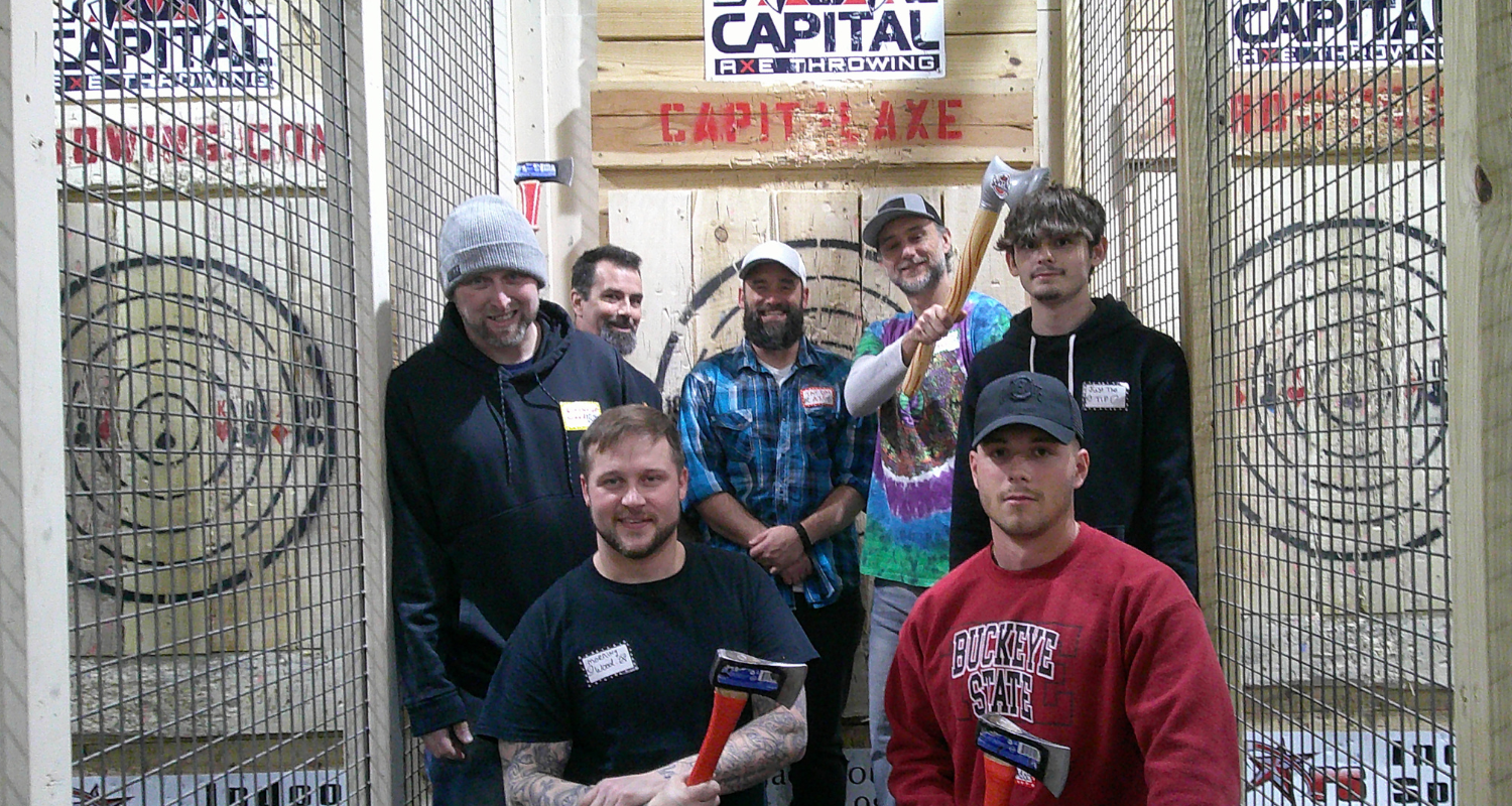 photo of a group of men posing with axes at an axe throwing venue